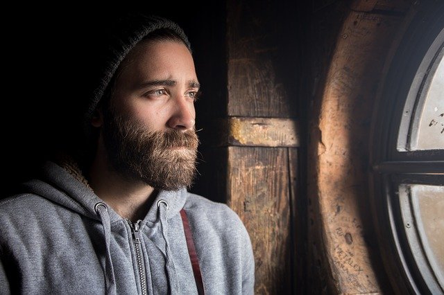 Cristãos Pentecostais Preconceituosos - Imagem de homem com barba olhando ao relento por uma janela antiga