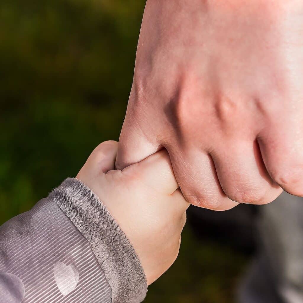 Imagem de uma mão de uma criança segurando a mão de um adulto, ilustrando confiança no artigo Palavra Bíblica do Dia 01-01-2023 no site conselheirocristao.com.br