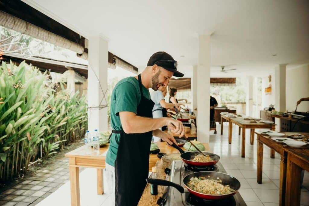 A chef prepares a meal in an open-air kitchen setting in Bali, Indonesia.