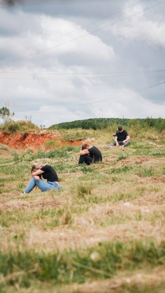 Você já orou hoje? a group of people sitting on top of a grass covered field