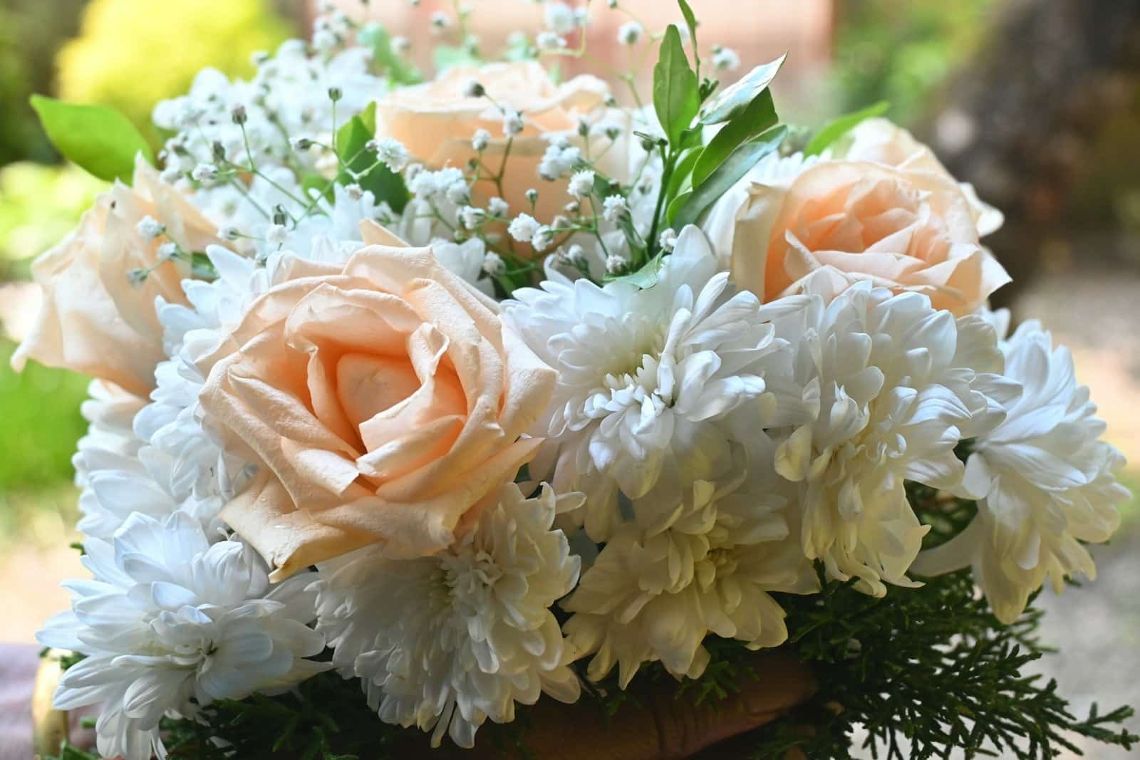 A bouquet of white and peach flowers in someone's hand