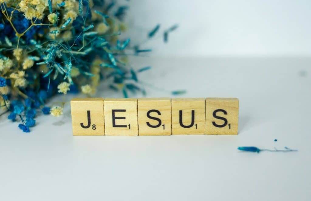 Discipulado: a wooden block spelling jesus next to a bouquet of flowers